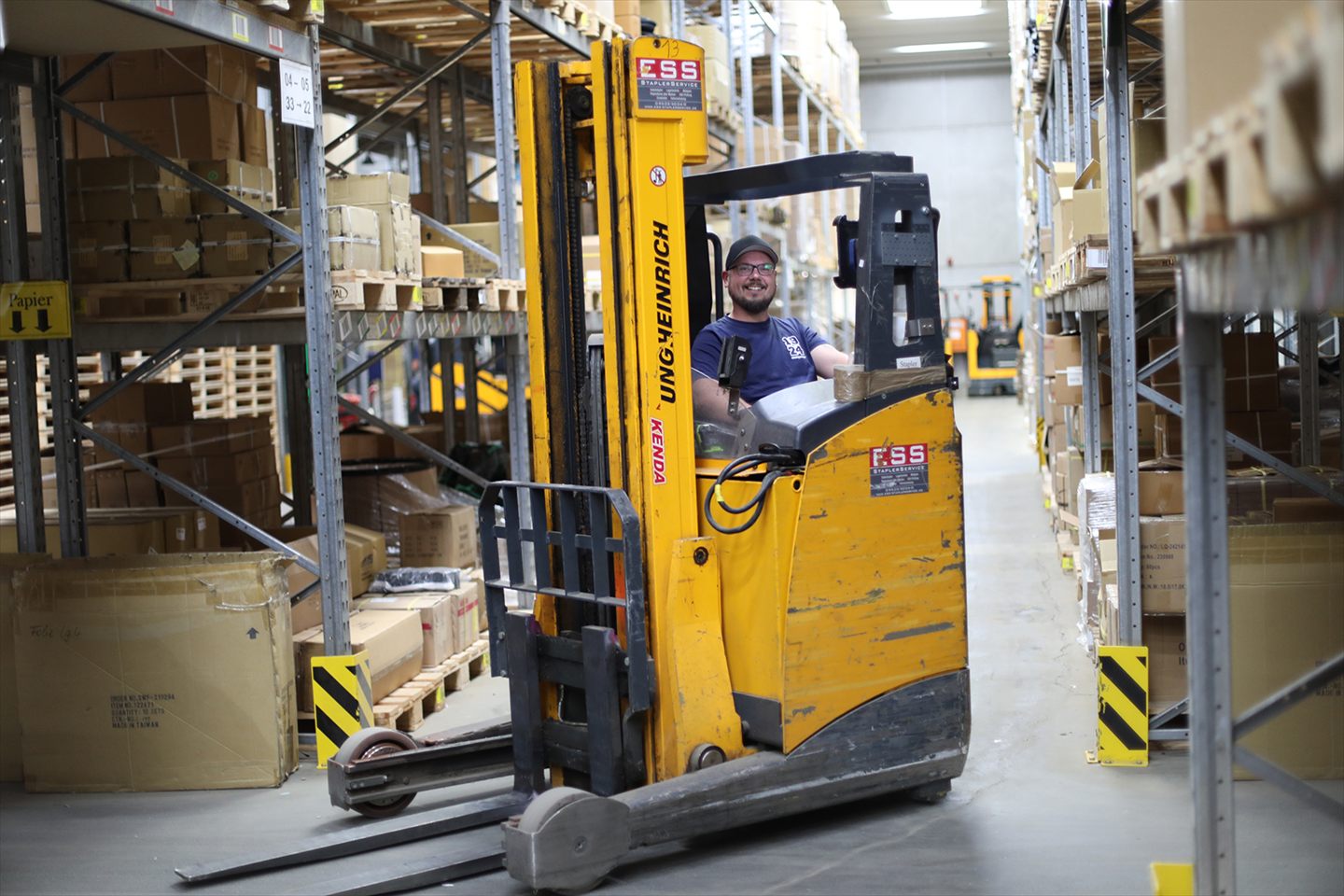 An employee driving a forklift through the warehouse